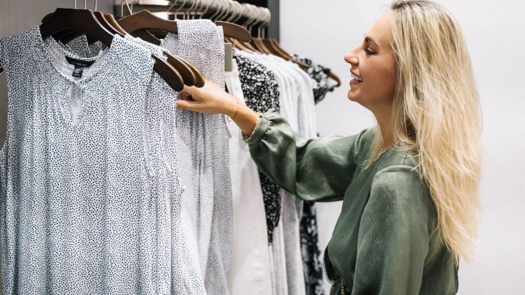 Femme devant un portant de chemisier dans une boutique