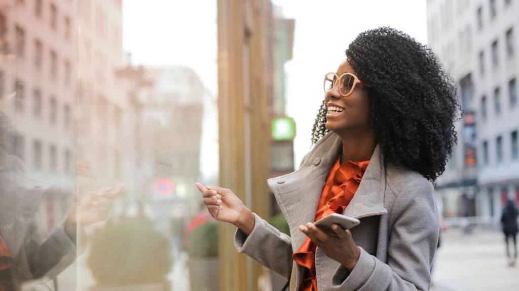 Jeune femme dans la rue avec un portable à la main