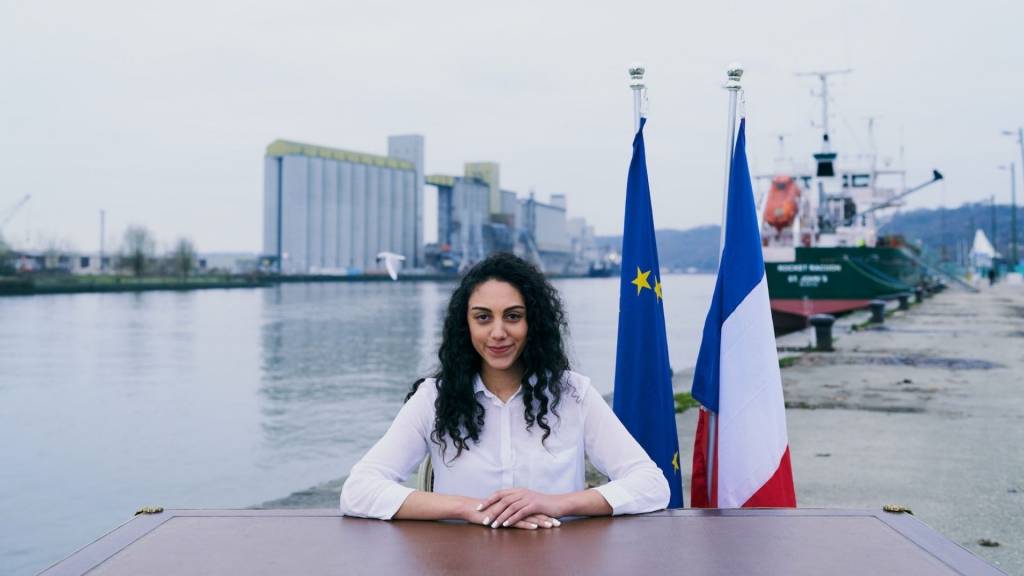 Jeune femme assise derrière un bureau avec les drapeaux français et européen