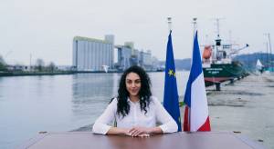 Jeune femme assise derrière un bureau avec les drapeaux français et européen