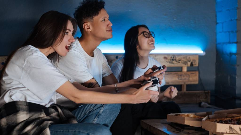 Xsolla accroît les opportunités de revenus pour les développeurs de jeux mobiles avec sa solution de boutique en ligne Trois personnes jouant à un jeu vidéo dans leur salon