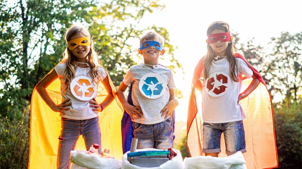 3 enfants masqués tel des super héros, avec chacun un logo de recyclage sur son t-shirt et une cape