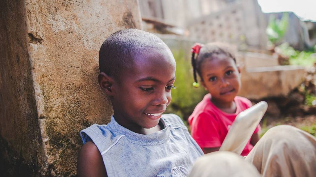 2 jeunes enfants africains, assis, devant un smartphone