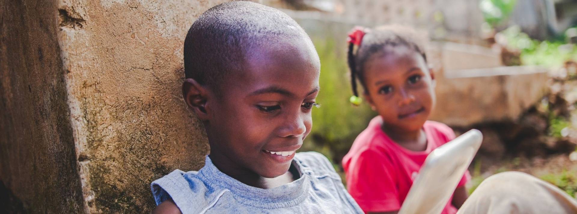 L’entreprise sociale française Kajou lève 1 million d’euros pour accélérer son développement en Afrique de l’Ouest 2 jeunes enfants africains, assis, devant un smartphone