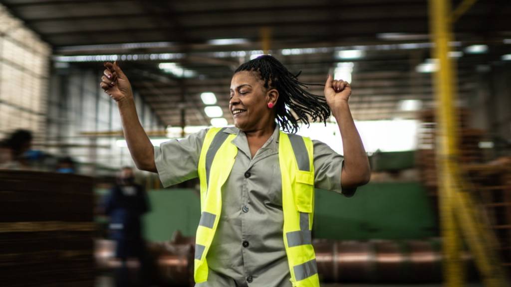 Femme, portant un gilet jaune, dansant dans un entrepot