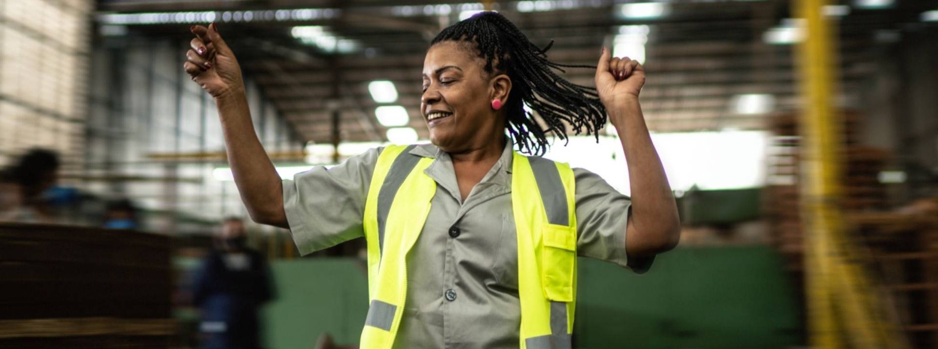 Actual group lance un nouveau dispositif de recrutement et d’accompagnement accessible à tous les demandeurs d’emploi dont les compétences ne correspondent pas aux besoins des entreprises Femme, portant un gilet jaune, dansant dans un entrepot