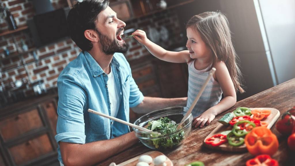 Petite fille faisant manger des légumes à son papa