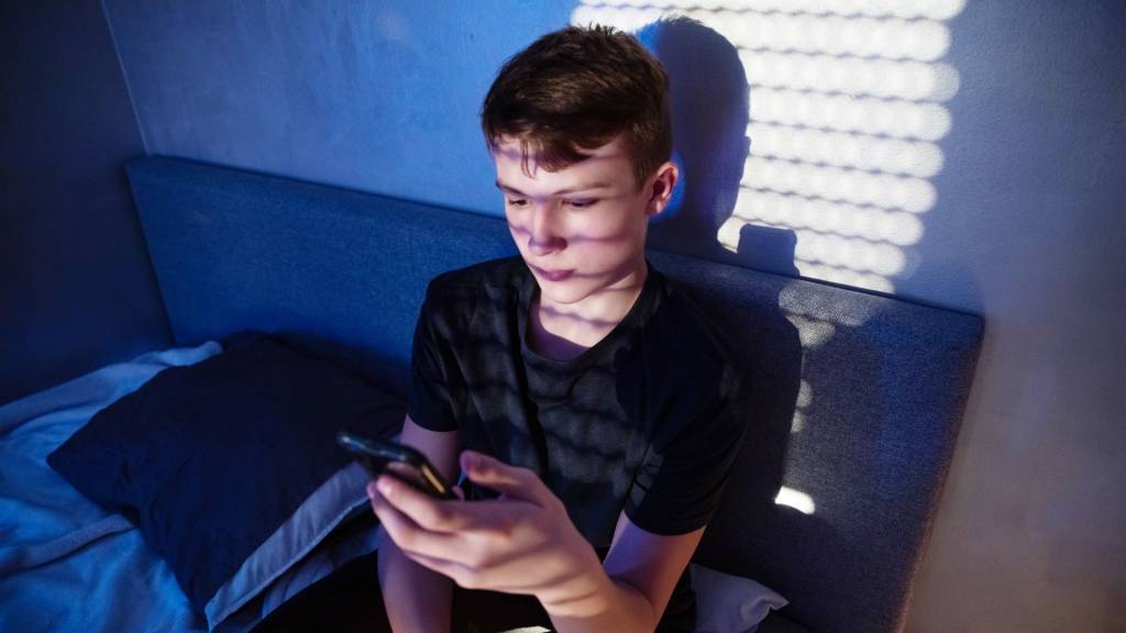 Ado devant un smartphone dans sa chambre