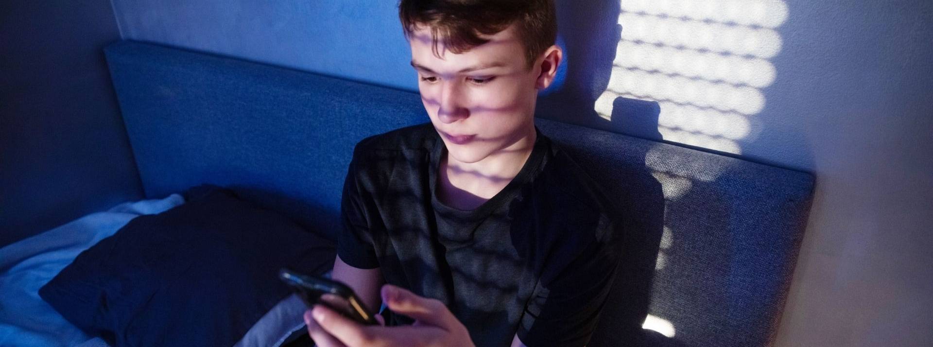 Le site public et gratuit FamiNum.com propose aux familles des solutions pour désamorcer les problèmes liés aux écrans au quotidien. Ado devant un smartphone dans sa chambre