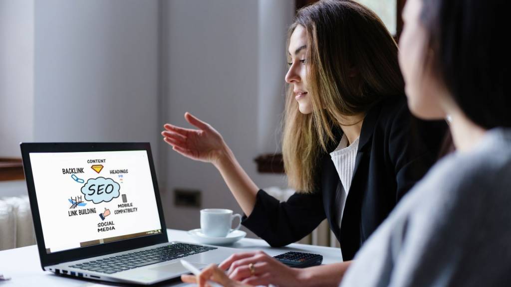 Concept d’optimisation des moteurs de recherche (SEO) sur l’écran de l’ordinateur avec deux femmes d’affaires dans le bureau