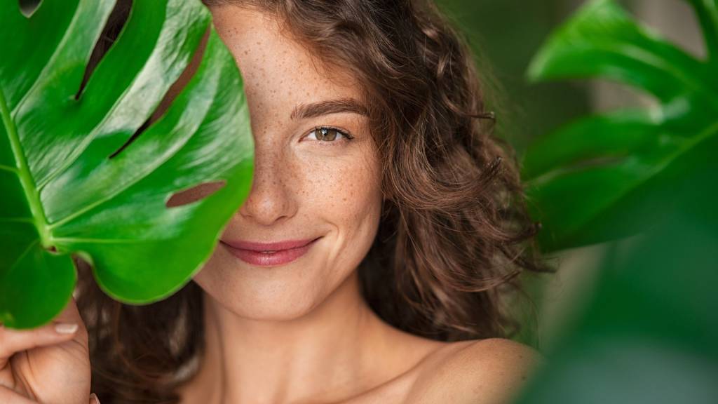 Femme couvrant son visage avec une feuille tropicale