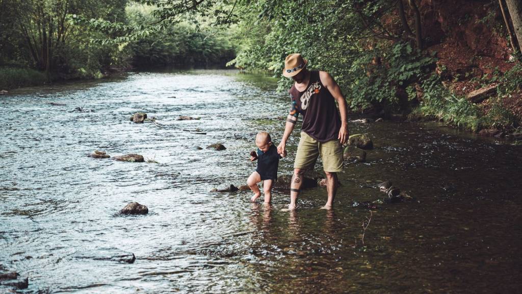 Papa avec son fils marchant dans une rivière