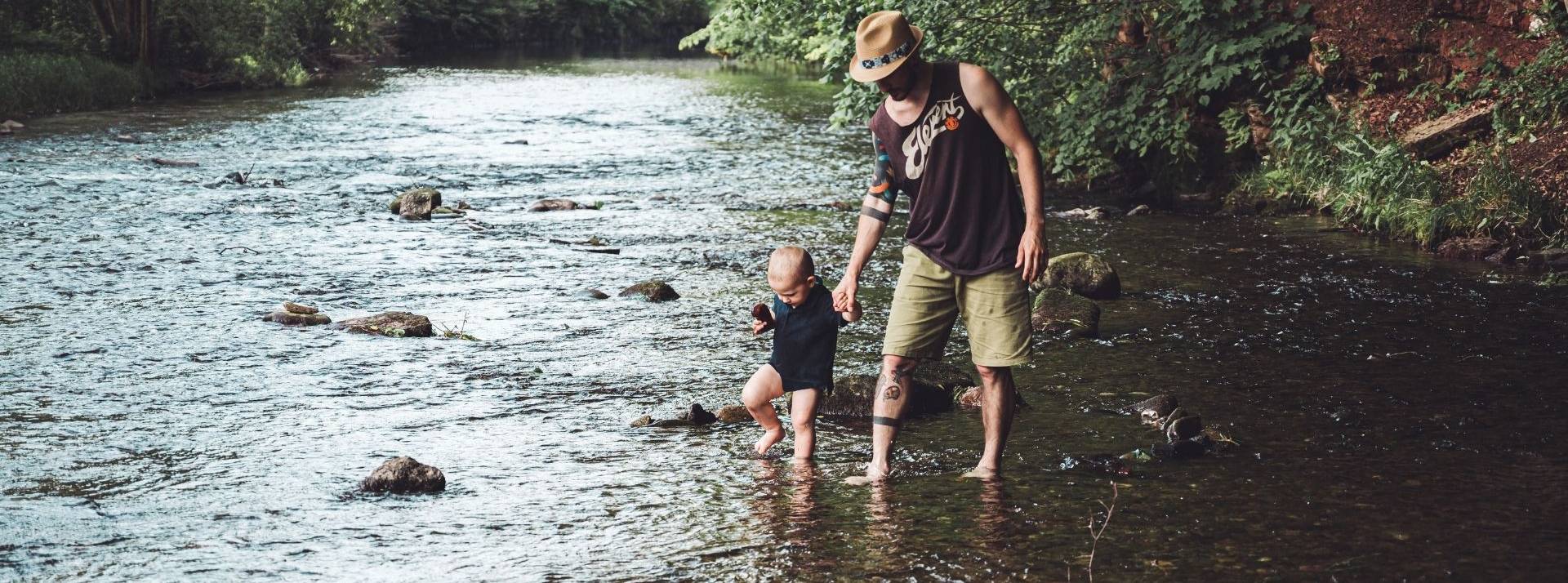Goodvest Kids : la première épargne compatible avec l'Accord de Paris est disponible pour les mineurs Papa avec son fils marchant dans une rivière