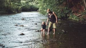 Papa avec son fils marchant dans une rivière