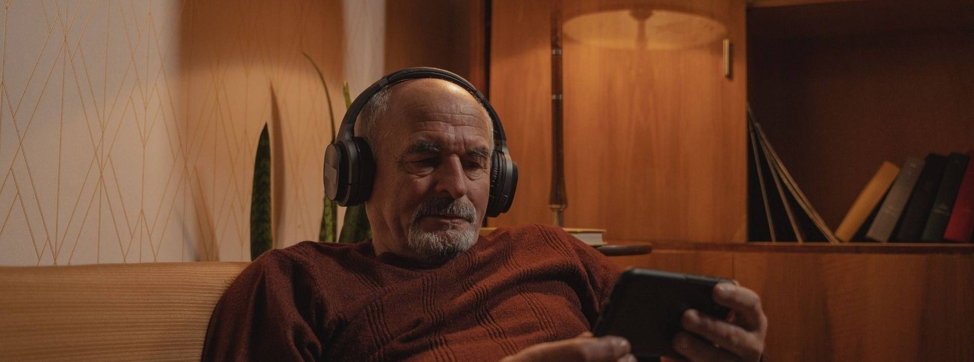 YouTube propose des épisodes de séries gratuits, financées par la diffusion de Homme assis dans un canapé regardant son smartphone avec un casque sur les oreilles