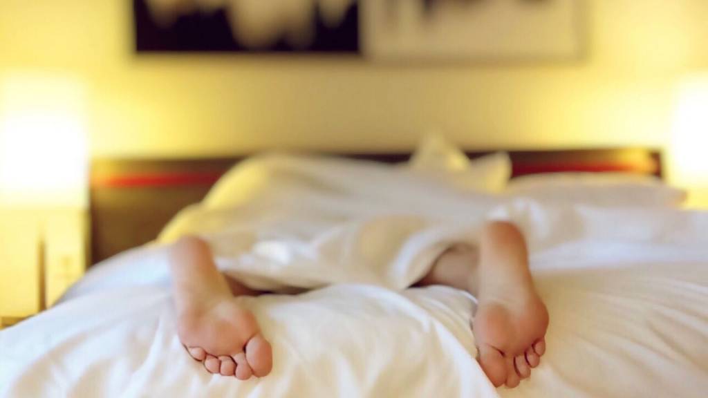 Personne allongé sur un lit, dont on ne voit que les pieds qui dépassent