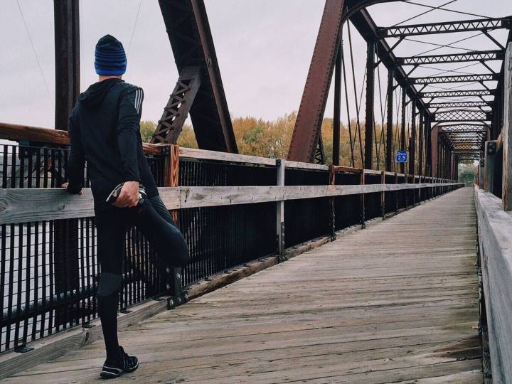 Homme faisant son jogging et s'étirant sur un pont