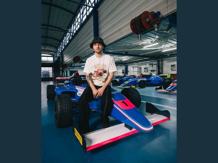 Squeezie assis sur la capot d'une formule 4
