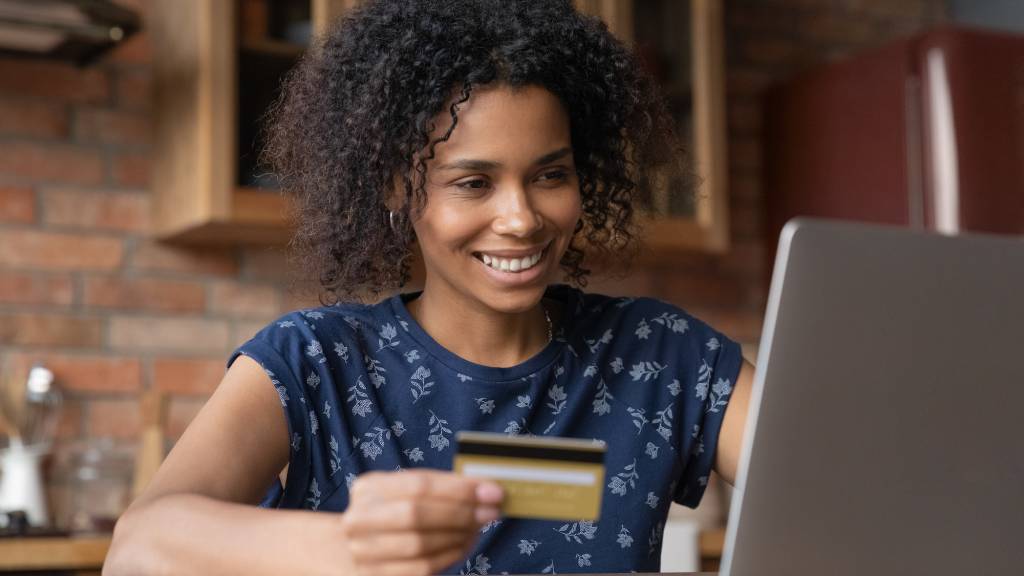 Happy biracial female buy goods at internet using gold card