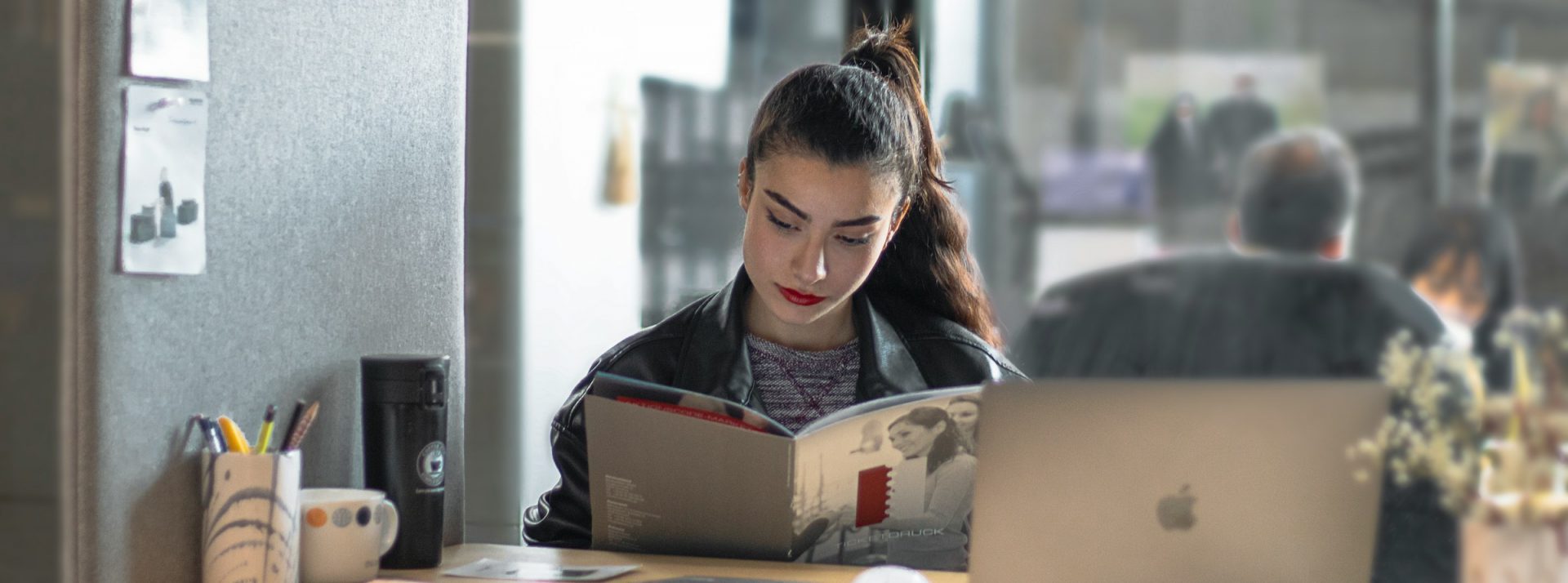 Papier ou numérique : le vrai du faux sur leur impact écologique femme qui lit un ouvrage avec un ordinateur sur son bureau